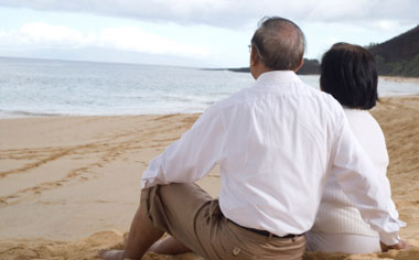 image of an older couple sitting on the sand at the beach